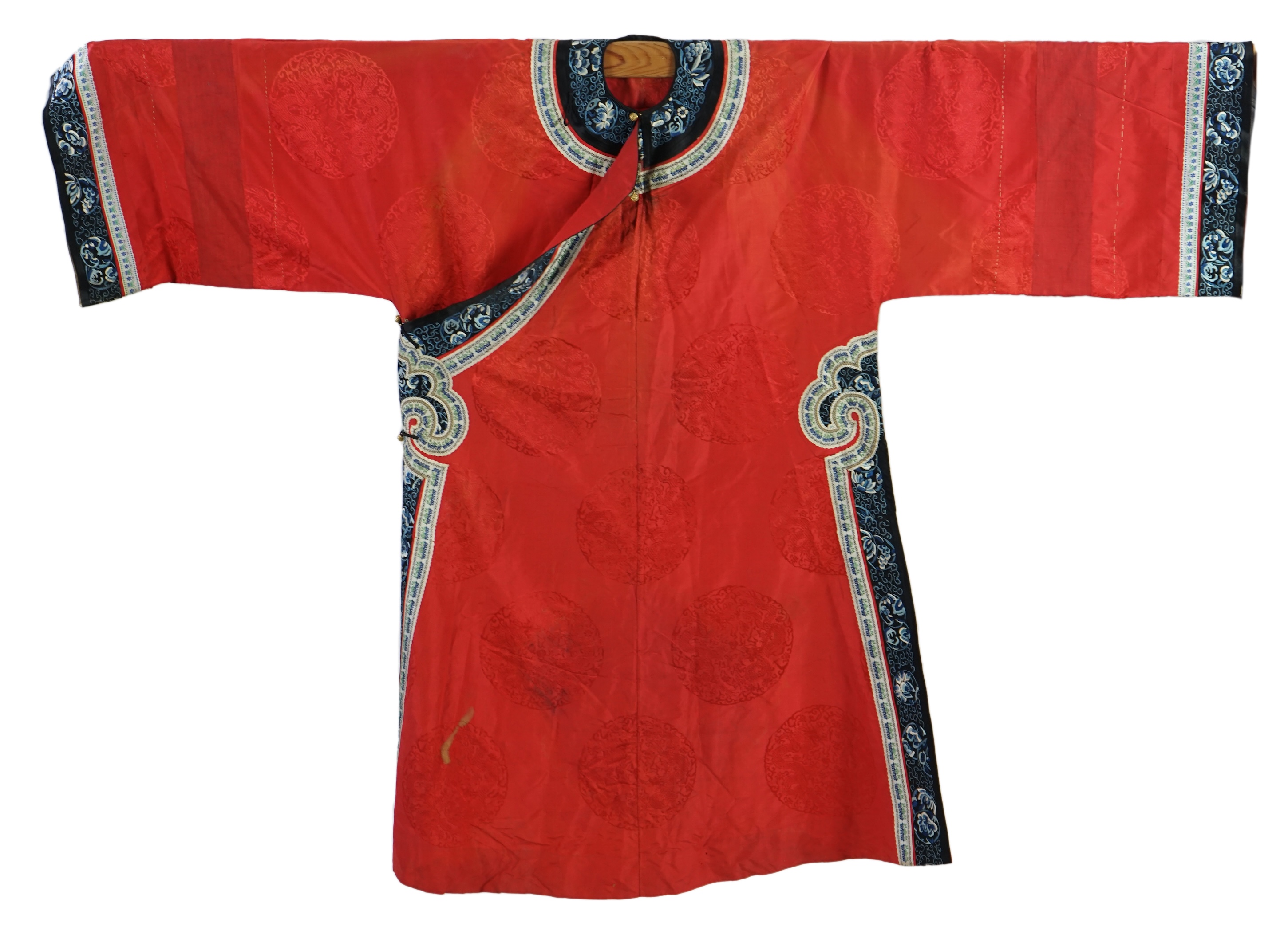 A late 19th century Chinese Manchu ladies red silk damask robe, with black and blue silk embroidered borders, ornately edged cream floral silk braiding, length from neck (back) to bottom edge 132cm long. Condition - stai